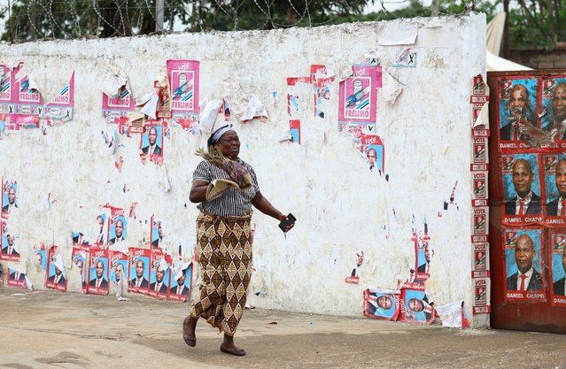 A woman reacts to teargas as she runs past posters of FRELIMO, during a nationwide strike called by Mozambique presidential candidate Venancio Mondlane to protest the provisional results of an October 9 election, in Maputo, Mozambique on October 21, 2024. (Photo by Siphiwe Sibeko/Reuters)