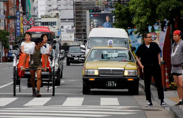 A man pulls tourists in a rickshaw past a taxi of Nissan Motor Co's Cedric in Tokyo, Japan June 1, 2017. (Photo by Toru Hanai/Reuters)