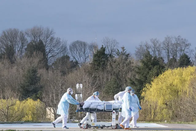 Medical staff push a patient on a gurney to a waiting medical helicopter at the Emile Muller hospital in Mulhouse, eastern France, to be evacuated on another hospital on March 17, 2020, amid the outbreak of the new Coronavirus, COVID-19. A strict lock down requiring most people in France to remain at home came into effect at midday on March 17, 2020, prohibiting all but essential outings in a bid to curb the coronavirus spread. The country has reported 148 deaths from the virus, a number that health experts warn could soar in the coming days, seriously straining the hospital system. (Photo by Sebastien Bozon/AFP Photo)