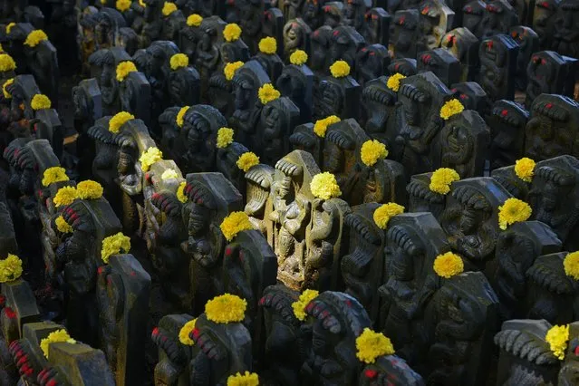 Stone sculptures of snakes are adorned with flowers placed by Hindu devotees on the occasion of “Naga Panchami”, an auspicious day in the Hindu calendar in which serpents are worshipped, in Bangalore on August 2, 2022. (Photo by Manjunath Kiran/AFP Photo)