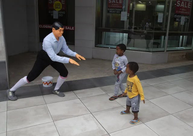 A mime artist performs for two children after getting a donation at a virtually empty Mall in Johannesburg, Sunday, March 22, 2020. There is a noticeable drop in crowds of shoppers at malls due the spread of the coronavirus. (Photo by Denis Farrell/AP Photo)