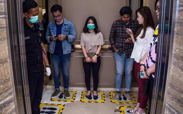 People stand on designated areas to ensure social distancing inside an elevator at a shopping mall in Surabaya on March 19, 2020, amid concerns of the COVID-19 coronavirus outbreak. (Photo by Juni Kriswanto/AFP Photo)
