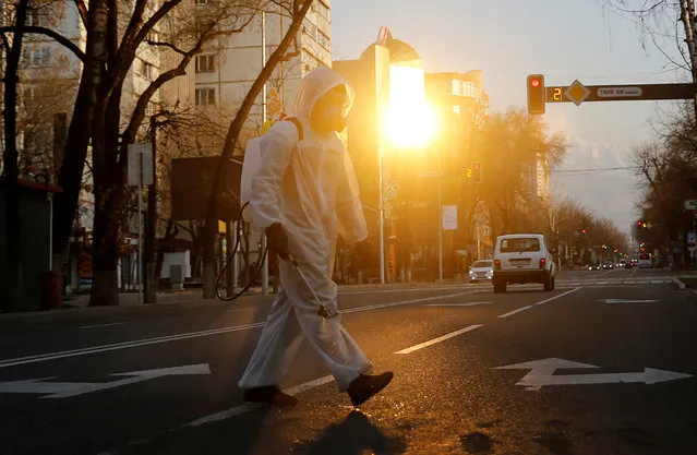 A specialist wearing protective gear sanitizes public facilities to prevent the spread of coronavirus disease (COVID-19) during sunset in Almaty, Kazakhstan on March 30, 2020. (Photo by Pavel Mikheyev/Reuters)