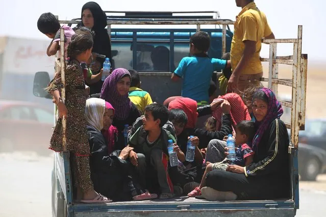 Iraqi women and children who fled the towns of al-Shirqat and Qayyarah during reported fighting between Iraqi government forces and jihadists of the Islamic State (IS) group, are transferred to a camp for displaced people on July 27, 2016. IS overran large areas north and west of Baghdad in 2014, but Iraqi forces have since regained significant ground and are conducting operations to set the stage for the battle to recapture Mosul, the last IS-held city in the country. (Photo by Ahmad Al-Rubaye/AFP Photo)