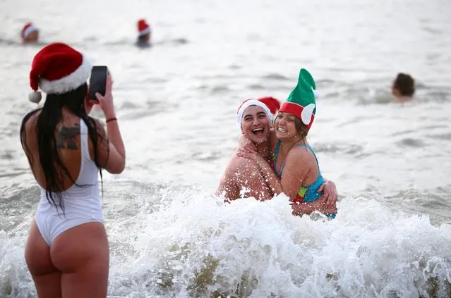 People participate in a Christmas Day dip on Brighton beach in southern England, Britain, December 25, 2021. (Photo by Hannah McKay/Reuters)
