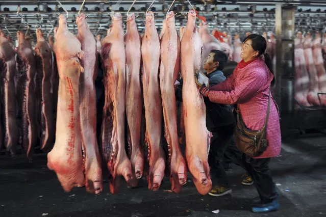 Customers choose slaughtered pigs at a wholesale pork market in Hefei, Anhui province in this December 5, 2012 file photo. People in China eat more than half the pork consumed in the world but domestic supplies come mainly from small farms that cut their herds whenever costs rise, causing boom-and-bust cycles that have led to record-high hog prices in 2015. (Photo by Reuters/Stringer)