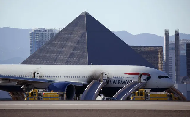 Casinos along the Las Vegas Strip can be seen behind a plane that caught fire at McCarren International Airport, Tuesday, September 8, 2015, in Las Vegas. An engine on the British Airways plane caught fire before takeoff. (Photo by John Locher/AP Photo)