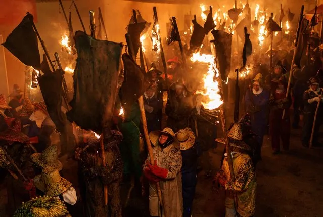 Participants wearing hat and gloves to protect from burns carry torches made out of wineskins in flames, during “El Vitor” torche procession, in Mayorga on September 27, 2022. The tradition of the procession of “El Vitor de Mayorga” dates back to the 18th century when villagers took to streets with torches to celebrate the arrival of the relics of Spanish Saint Toribius of Mogrovejo, who served as Archbishop of Lima. (Photo by Cesar Manso/AFP Photo)