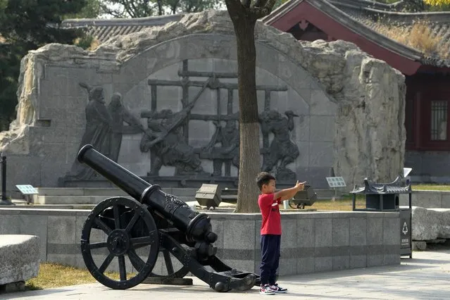 A child gestures holding a gun as he poses near a canon at Lugou Bridge also known as Marco Polo Bridge where it is generally remembered as the place from which an incident in 1937 started the Second Sino-Japanese War in Beijing, Tuesday, September 27, 2022. (Photo by Ng Han Guan/AP Photo)