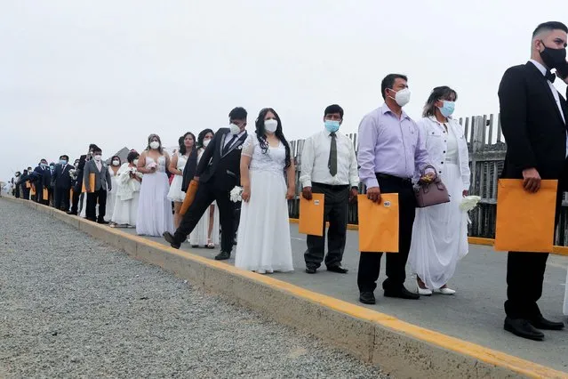 Couples stand in line before getting married in a mass wedding ceremony on the beach, in Lima, Peru on December 11, 2021. (Photo by Sebastian Castaneda/Reuters)