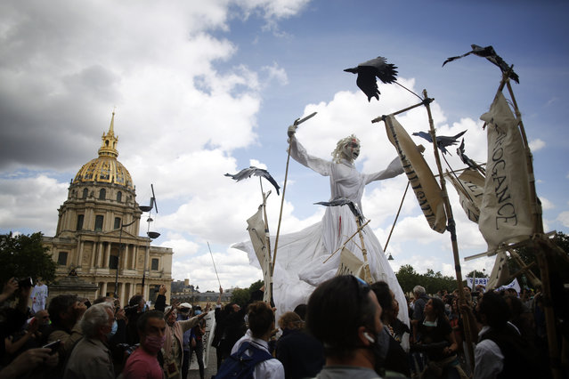 A giant puppet is paraded during a demonstration of hospitals workers, Tuesday, June 16, 2020 in Paris. French hospital workers and others are protesting in cities around the country to demand better pay and more investment in France's public hospital system, which is considered among the world's best but struggled to handle a flux of virus patients after years of cost cuts. France has seen nearly 30,000 virus deaths. (Photo by Thibault Camus/AP Photo)