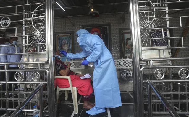 A health worker takes a swab test of a women at a temple in Mumbai, India, Saturday, July 18, 2020. India crossed 1 million coronavirus cases on Friday, third only to the United States and Brazil, prompting concerns about its readiness to confront an inevitable surge that could overwhelm hospitals and test the country's feeble health care system. (Photo by Rafiq Maqbool/AP Photo)
