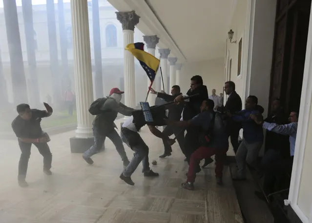 Opposition lawmakers brawl with pro-government militias who are trying to force their way into the National Assembly during a special session coinciding with Venezuela's independence day, in Caracas, on July 5, 2017. At least five lawmakers were injured in the attack. (Photo by Fernando Llano/AP Photo)