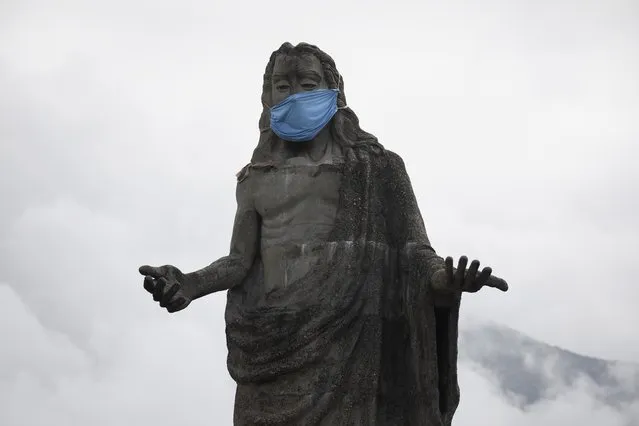 A protective face mask adorns a Jesus Christ statue as a reminder for residents to wear masks as a precaution against the spread of the new coronavirus, in the Petare neighborhod in Caracas, Venezuela, Friday, July 17, 2020. (Photo by Ariana Cubillos/AP Photo)