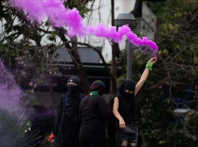 A demonstrator holds a flare during a protest against the violence against the women in Mexico City, Sunday, August 16, 2020. (Photo by Fernando Llano/AP Photo)