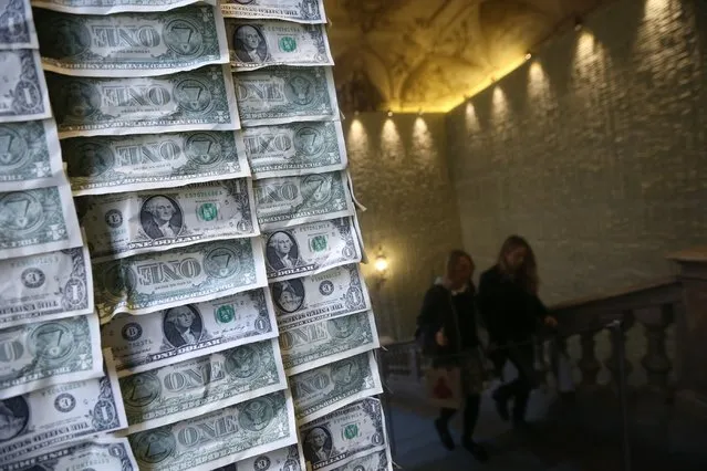 People walk past an installation by artist Eric Doeringer called “The Hug” showing 40.000 One dollar bills during the exhibition “sh*t and Die” as part of the “Artissima” art fair at Palazzo Cavour on November 5, 2014 in Turin. For its twenty-first edition Artissima feature a selection of 194 cutting-edge contemporary art galleries and a show “sh*t and Die” organised by Maurizio Cattelan, Myriam Ben Salah and Marta Papini at Palazzo Cavour. (Photo by Marco Bertorello/AFP Photo)