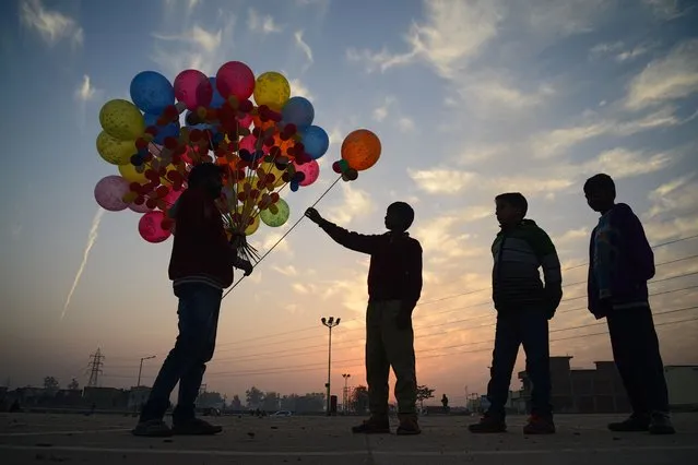 Indian children buy balloons from a street vendor in Jalandhar on January 10, 2018. (Photo by Shammi Mehra/AFP Photo)