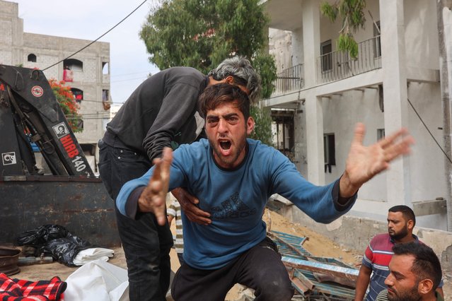 A Palestinian man mourns as others transport bodies of people killed in strikes on Jabalia a day earlier, at Al-Shifa hospital in Gaza City on June 23, 2025. (Photo by Omar Al-Qattaa/AFP Photo)