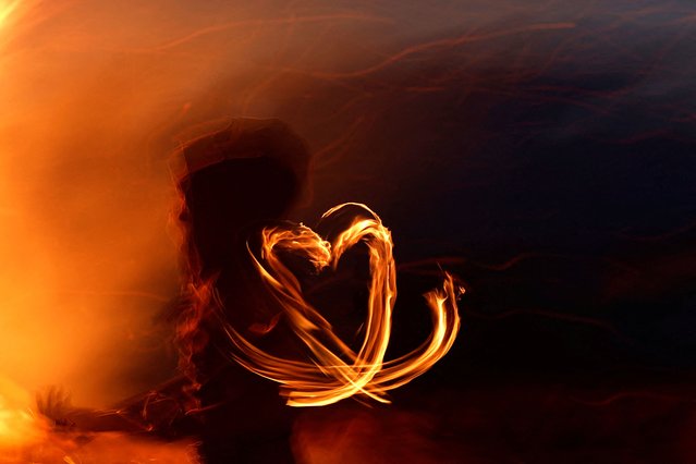 A fire dancer makes a heart shape at the Bealtaine fire festival, marking the beginning of summer at the Hill of Uisneach in Rathnew, Ireland, on May 10, 2025. (Photo by Clodagh Kilcoyne/Reuters)