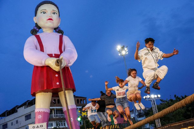 People play a skipping rope game with giant dolls named “Young-hee” and 'Chul-su' from Netflix series “Squid Game” during a promotional event of “Squid Game 3” final season at City Hall Square in Bangkok, Thailand on June 30, 2025. (Photo by Chalinee Thirasupa/Reuters)