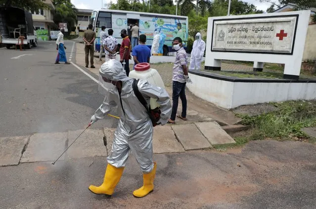 A Sri Lankan health worker sprays disinfectants as people wait to give swab samples to test for COVID-19 near a mobile testing vehicle outside a hospital in Minuwangoda, Sri Lanka, Tuesday, October 6, 2020. (Photo by Eranga Jayawardena/AP Photo)