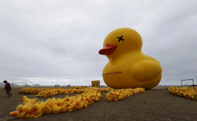 A giant inflatable doll in the shape of a duck is seen on Copacabana beach, in Rio de Janeiro, Brazil, October 25, 2015. The campaign "I will not pay the Duck" is organized by the Federation of Industries of Rio de Janeiro (FIRJAN) and uses the duck symbol in reference to industries that pay high taxes. (Photo by Sergio Moraes/Reuters)