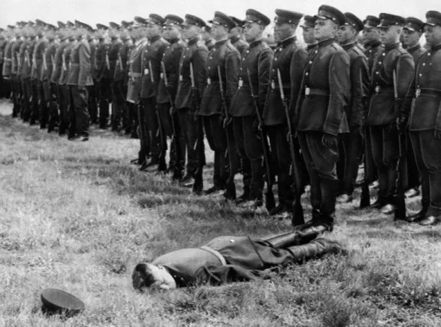 A Soviet soldier is flattened after fainting at a parade of Russian soldiers at Brandenburg airfield in East Germany, June 20, 1956. The ceremonies were connected with the withdrawal of a promised 33,500 Russian troops from East Germany. (Photo by AP Photo)