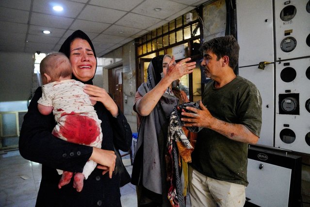 A woman carries her child following the Israeli strikes on Iran, in Tehran, on June 15, 2025. (Photo by Amir Kholousi/WANA via Reuters)