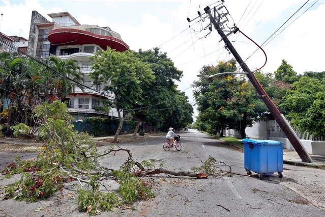 A woman on a bicycle passes next to the branches of a fallen tree and a crooked electric pole after the passage of Tropical Storm Laura, in Havana, Cuba, 25 August 2020. Cuba began on 25 August throughout its territory the recovery and evaluation phase of the damage caused by tropical storm Laura, which between 23 and 24 August traveled the island from end to end without leaving victims but damaging the electrical networks, homes and crops. (Photo by Ernesto Mastrascusa/EPA/EFE)