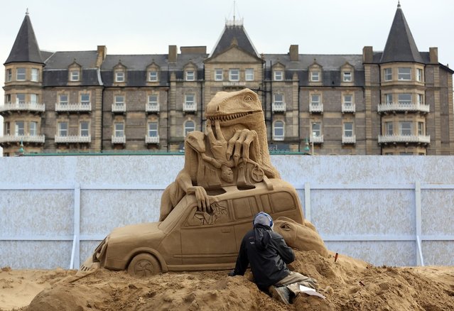A sand sculptor works on a Jurassic Park themed sand sculpture as pieces are prepared as part of this year's Hollywood themed annual Weston-super-Mare Sand Sculpture festival on March 26, 2013 in Weston-Super-Mare, England. Due to open on Good Friday, currently twenty award winning sand sculptors from across the globe are working to create sand sculptures including Harry Potter, Marilyn Monroe and characters from the Star Wars films as part of the town's very own movie themed festival on the beach.  (Photo by Matt Cardy)