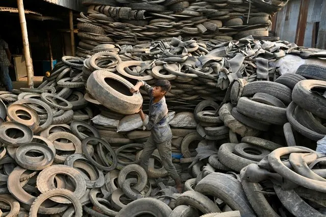 A worker piles up discarded truck tyres for recycling in Dhaka on February 8, 2023. (Photo by Munir Uz Zaman/AFP Photo)