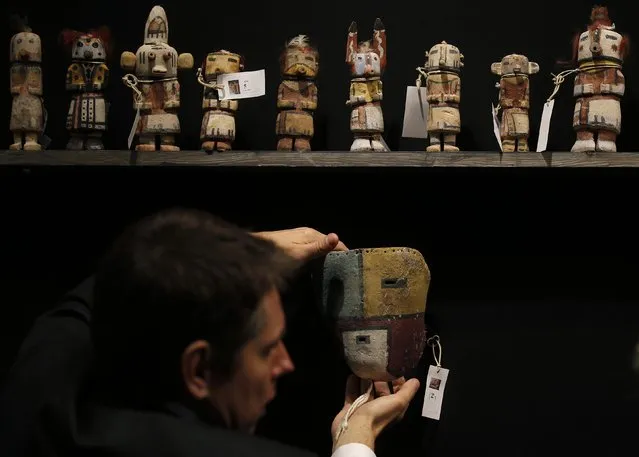 An expert hangs a rare antique Tuma Uyim mask below Kachina dolls made by the Native American Hopi and Zuni tribes displayed at the Drouot auction house in Paris before auction, December 15, 2014. (Photo by Christian Hartmann/Reuters)