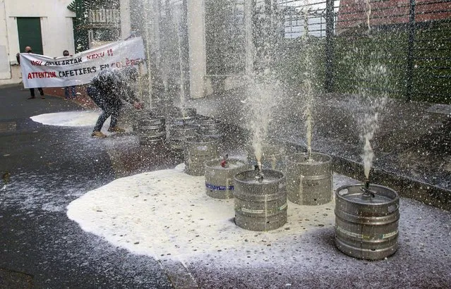 A bar owner opens casks of beer in front of a local administration center in Bayonne, southwestern France, Friday, November 27, 2020, as he stages a protest against the nation wide lockdown. France's health minister said Thursday his country is readying to start administering COVID-19 vaccines in late December but warned that people will still have to wear masks and keep their distance even after vaccines are widely available. (Photo by Bob Edme/AP Photo)