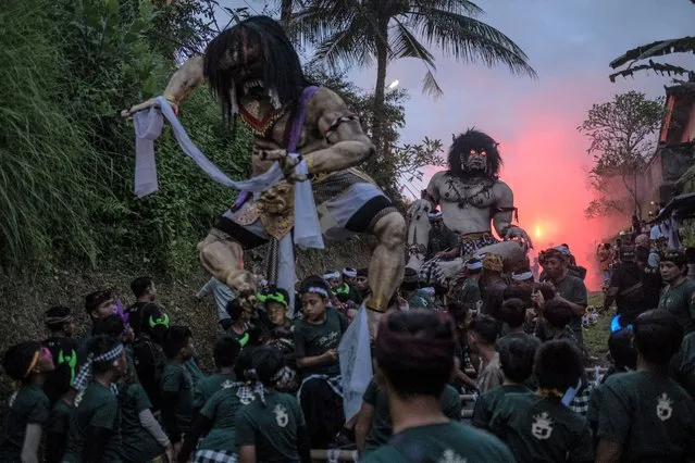 Balinese kids carry the ogoh-ogoh, the giant menacing-looking dolls during the ogoh-ogoh parade on the eve of Nyepi, the Balinese Hindu Day of Silence that marks the arrival of the new Saka lunar year on March 20, 2023 in Tegalalang Village, Gianyar, Bali, Indonesia. Balinese Hindus perform a series of rituals in early March to celebrate the lunar new year, which culminates in the observance of Nyepi. The Ogoh-ogoh became a staple of the parade in the early 1980s. Prior to that, the participants roamed the streets carrying bamboo torches and making loud noises with percussion instruments to scare away the demons. In present-day Bali, the majority of ogoh-ogoh are built by members of seka teruna teruni, the youth wing of banjar. Nyepi comes from the word sepi or sipeng which means lonely, quiet, silent, zero, empty, no crowd, no noise, and no activity. Since 1983, Nyepi has been a national holiday. The celebration of the Nyepi festivities for Balinese Hindus in Indonesia is an opportunity for self-reflection which is called mulat sarira. All residents and visitors are required to abide by the rules called Catur Brata Penyepian, consisting of: no open fires or flames, no pleasurable activities, no work or labor, and no journeys.(Photo by Agung Parameswara/Getty Images)