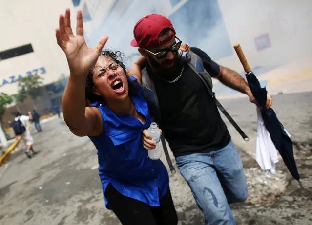 A woman affected by tear gas is assisted during a May Day protest against austerity measures, in San Juan, Puerto Rico May 1, 2018. (Photo by Alvin Baez/Reuters)