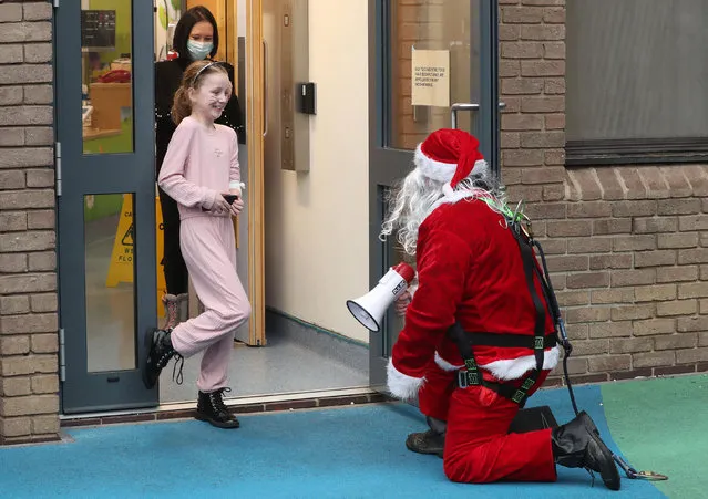 A man dressed as Santa Claus kneels outside the building as he speaks to Darcie Jones, aged 8, through an open doorway as he visits patients at Children's Hospital in Leeds, England on December 21, 2020. (Photo by Danny Lawson/PA Images via Getty Images)