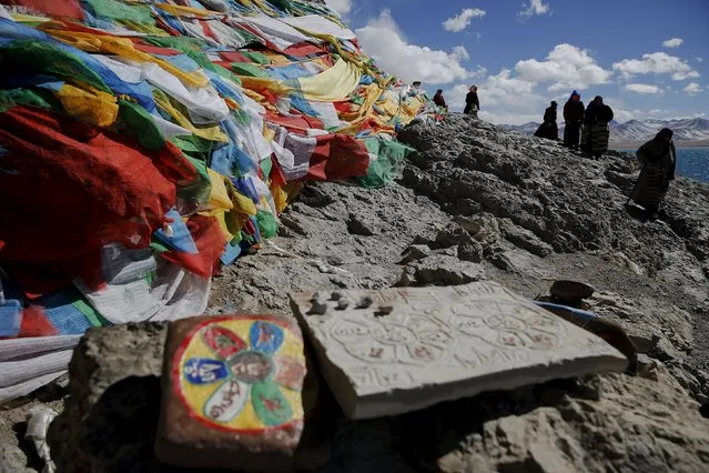 Tibetan people circle around a rock decorated with prayer flags at Namtso lake in the Tibet Autonomous Region, China November 18, 2015. (Photo by Damir Sagolj/Reuters)