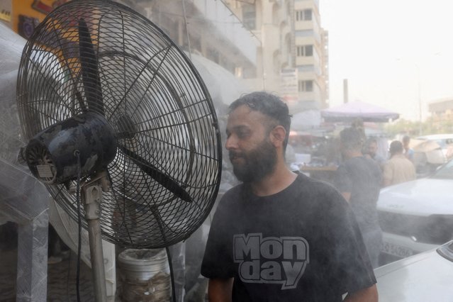 A man cools his face with water mist from sprinklers during a heatwave in Baghdad, Iraq on July 28, 2025. (Photo by Ahmed Saad/Reuters)