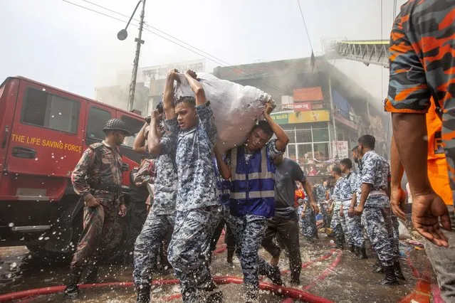 Bangladesh Navi personnel help clear the area while firefighters try to put out a fire at the New Super Market in Dhaka, Bangladesh, 15 April 2023. According to Fire Service and Civil Defense, a fire broke out at the New Super Market and around thirty firefighting units were deployed with support from the army, the navy, the air force and Border Guard Bangladesh teams. The reason behind the fire was yet to be determined and no immediate casualties were reported. (Photo by Monirul Alam/EPA)