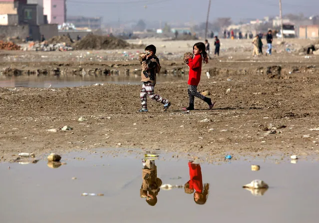 Afghan children are reflected in flood water as they make their way to play on the outskirts of Kabul, Afghanistan, Sunday, November 15, 2015. (Photo by Rahmat Gul/AP Photo)