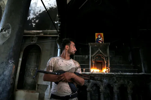 An Iraqi Christian soldier holds his weapon during the first Sunday mass at the Grand Immaculate Church since it was recaptured from Islamic State in Qaraqosh, near Mosul in Iraq October 30, 2016. (Photo by Ahmed Jadallah/Reuters)