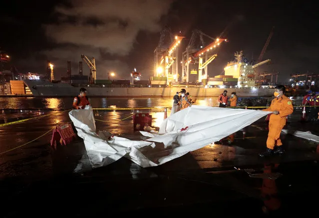 Members of National Search and Rescue Agency (BASARNAS) prepare an area where debris found in the waters where a Sriwijaya Air passenger jet has lost contact with air traffic controllers will be brought to be examined, at Tanjung Priok Port in Jakarta, Indonesia, early Sunday, January 10, 2021. The Boeing 737-500 took off from Jakarta for Pontianak, the capital of West Kalimantan province on Indonesia's Borneo island with 56 passengers and six crew members onboard, and lost contact with the control tower a few moments later. (Photo by Dita Alangkara/AP Photo)