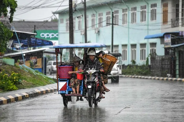 People ride a sidecar motorcycle in an almost empty street in Kyauktaw in Myanmar's Rakhine state on May 14, 2023, ahead of the expected landfall of Cyclone Mocha. (Photo by Sai Aung Main/AFP Photo)