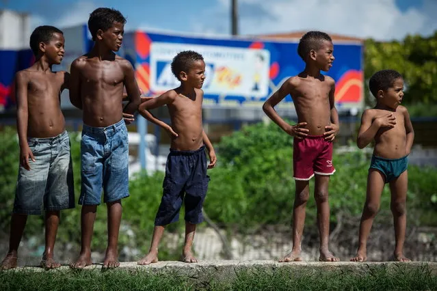 Boys look at friends playing football in a shantytown of Olinda, about 18 km from Recife in northeastern Brazil, on June 18, 2013 as the FIFA Confederations Cup Brazil 2013 football tournament is being held in the country. The historic centre of Olinda is listed as an UNESCO World Heritage Site. (Photo by Yasuyoshi Chiba/AFP Photo)