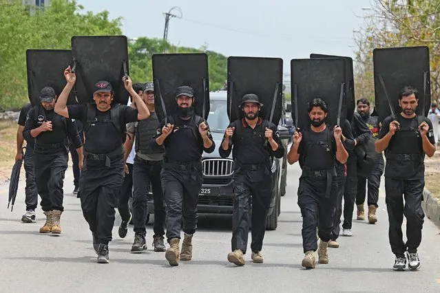 Security personnel with ballistic shields escort a vehicle carrying former Pakistan's prime minister Imran Khan as he leaves after appearing before an anti-terrorism court in Islamabad on May 23, 2023. (Photo by Aamir Qureshi/AFP Photo)