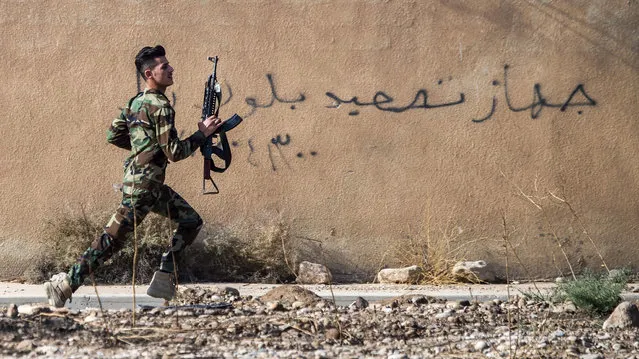A Peshmerga fighter runs to take position as the Iraqi Kurdish forces pushed deeper into the town of Bashiqa during street battles against Islamic State (IS) group jihadists on November 8, 2016. Capturing Bashiqa would be one of the final steps in securing the eastern approaches to Mosul, three weeks into an offensive by Iraqi forces to retake the country's second city.
The town was under the “complete control” of Kurdish peshmerga forces, Jabbar Yawar, the secretary general of the Kurdish regional ministry responsible for the fighters, told AFP. (Photo by Odd Andersen/AFP Photo)