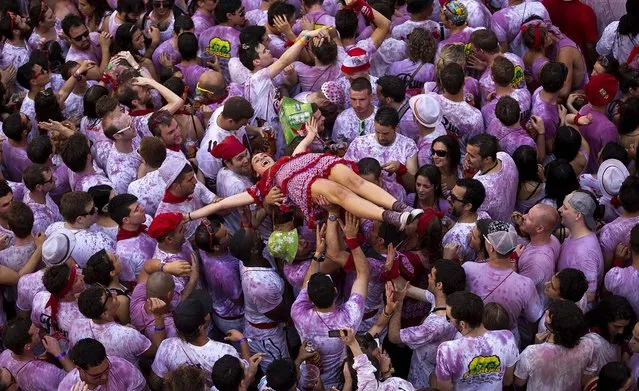 Revelers hold up a girl during the launch of the “Chupinazo” rocket, to celebrate the official opening of the 2013 San Fermin fiestas. (Photo by Daniel Ochoa de Olza/Associated Press)