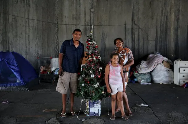 Ana Paula, 25, her husband Antonio Carlos, 32, and their daughter Kauani, 8, who are homeless and living underneath a bridge, pose next to a Christmas tree in Sao Paulo, Brazil, December 18, 2015. (Photo by Nacho Doce/Reuters)