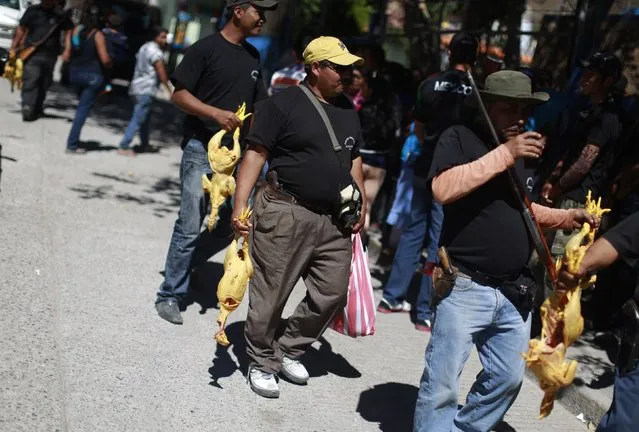 Members of the Community Police of the FUSDEG (United Front for the Security and Development of the State of Guerrero carry chickens for their lunch in the downtown of the village of Petaquillas, on the outskirts of Chilpancingo, in the Mexican state of Guerrero, February 1, 2015. (Photo by Jorge Dan Lopez/Reuters)
