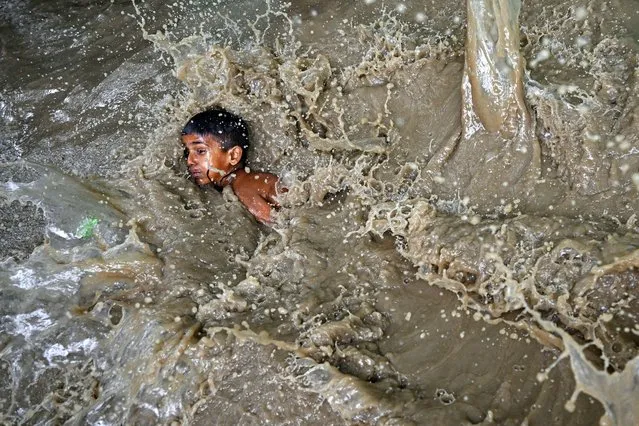 A boy plays in a flooded residential area near the banks of Yamuna River after it overflowed due to monsoon rains, in New Delhi on July 11, 2023. (Photo by Arun Sankar/AFP Photo)
